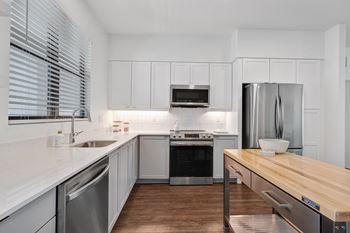 A kitchen with white cabinets and stainless steel appliances and a wooden counter top